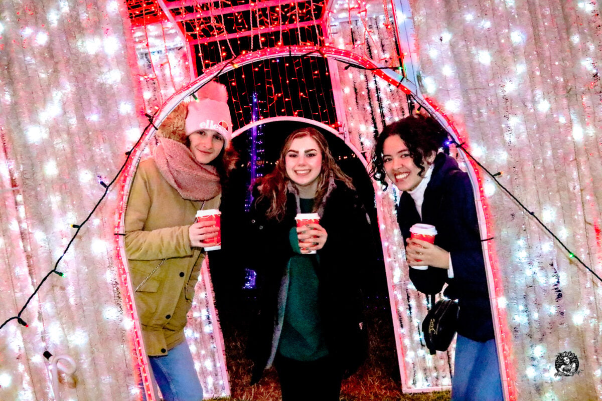 Friends walking together through a tunnel of holiday lights at the Maryland Holiday Light Spectacular
