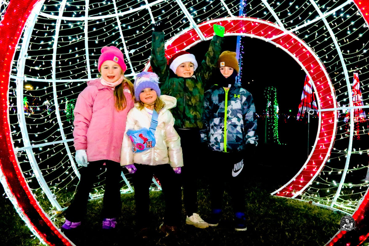 Children under a lit archway on the Christmas light trail at the Maryland State Fairgrounds in Timonium